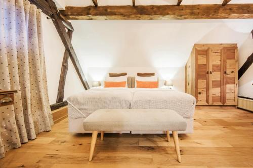 a bedroom with a white bed with a bench in it at Hotel Pok Garni in Brezovica