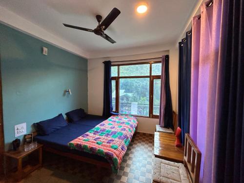 a bedroom with a bed and a ceiling fan at Peppy Nomads Apartment in Jibhi