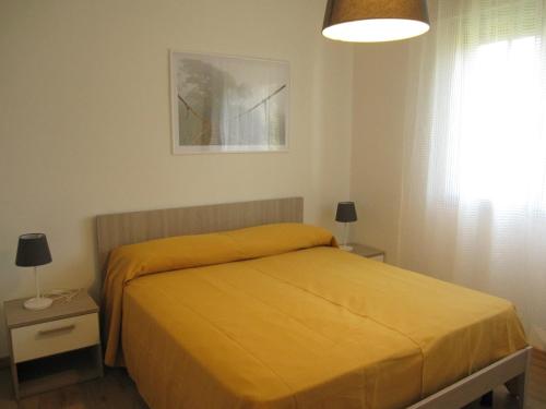 ein Schlafzimmer mit einem Bett mit gelber Tagesdecke in der Unterkunft Appartamento Vigna del Mar in Lido