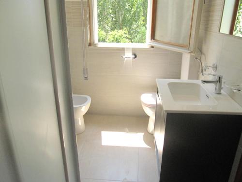 ein Bad mit einem Waschbecken, einem WC und einem Fenster in der Unterkunft Appartamento Vigna del Mar in Lido