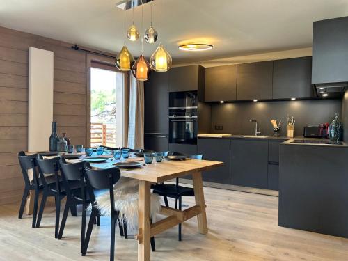 une cuisine avec une table en bois et des armoires noires dans l'établissement Appartement 3 Chambres au Centre des Gets avec Balcon, Parking et Cheminée - FR-1-623-333, aux Gets