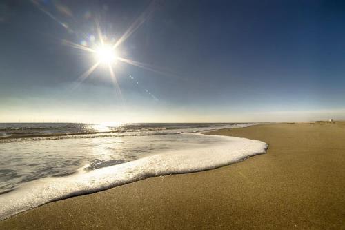 a beach with the sun shining on the water at Home Lea in Docking