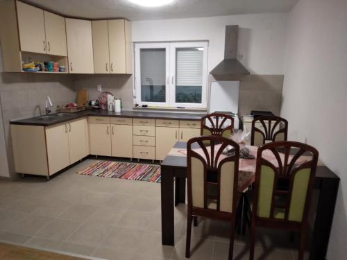 a kitchen with a table and chairs and a kitchen with a window at Vikendica Ninic in Laktaši