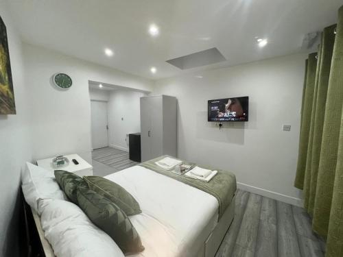 Central Harrow Cozy Apartment with free parking في Harrow on the Hill: غرفة نوم مع سرير وتلفزيون على الحائط