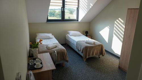 um quarto com 2 camas, uma mesa e janelas em Pensjonat Dębowy Dworek em Ciechocinek
