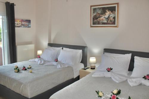 two beds in a bedroom with flowers on them at George Airport Apartments in Heraklio