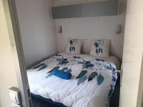 a bed with blue and white sheets and pillows at Camping Pré Vologne in Granges-sur-Vologne