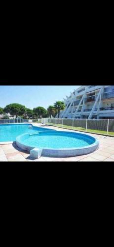 une grande piscine bleue avec un bâtiment en arrière-plan dans l'établissement Studio piscine plages à pied, à La Grande Motte