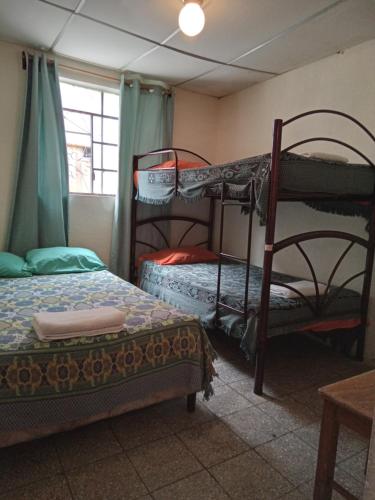 1 dormitorio con 2 literas y ventana en Huellas Hostal Antigua, en Antigua Guatemala
