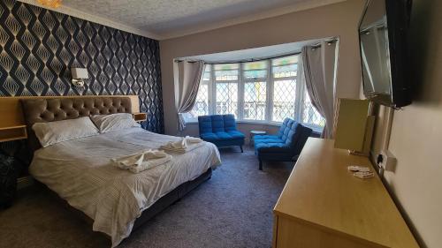 a bedroom with a bed and two blue chairs at The Kimberley B&B in Blackpool