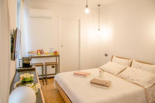 a white bedroom with a bed and a table with a table at A Mos Veure B&B in Alghero