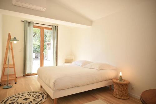 a white bedroom with a bed and a window at Domaine de Matourne in Flayosc