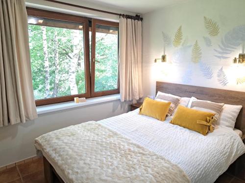 ein Schlafzimmer mit einem Bett mit gelben Kissen und einem Fenster in der Unterkunft Brzozowy Zakątek in Salzberg