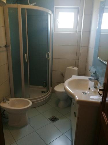 een badkamer met een douche, een toilet en een wastafel bij Apartmani Kuburović 1 in Sutomore