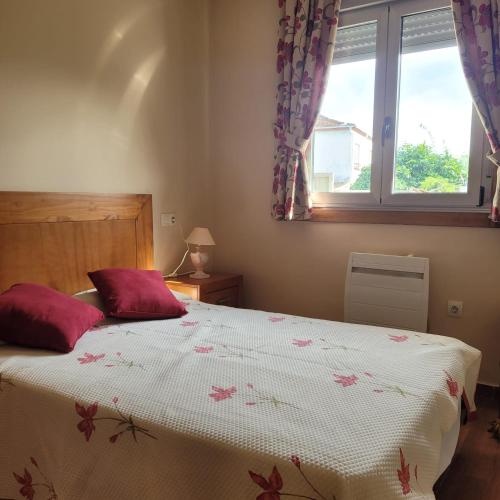 a bedroom with a bed with red pillows and a window at Casa Maside Orense in Maside