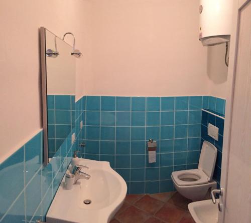 bagno piastrellato blu con lavandino e servizi igienici di Residence Lentischi a Castelsardo