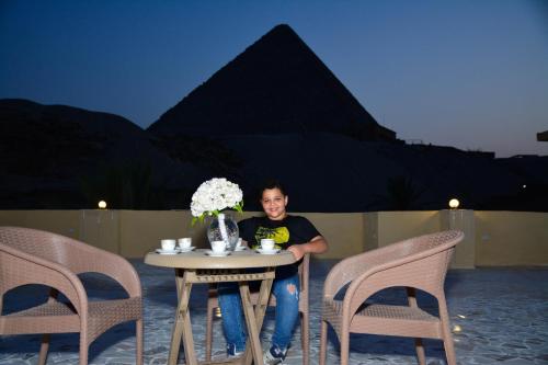 a man sitting at a table with a vase of flowers at Crystal pyramid inn in Cairo