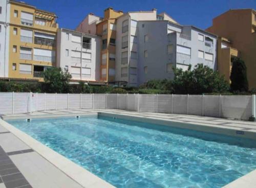 a swimming pool with buildings in the background at Studio - résidence avec piscine in Cap d'Agde