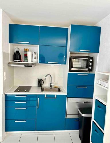 - une cuisine bleue avec évier et four micro-ondes dans l'établissement Studio - résidence avec piscine, au Cap d'Agde