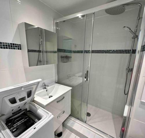 une salle de bain blanche avec une douche et un lavabo dans l'établissement Studio - résidence avec piscine, au Cap d'Agde