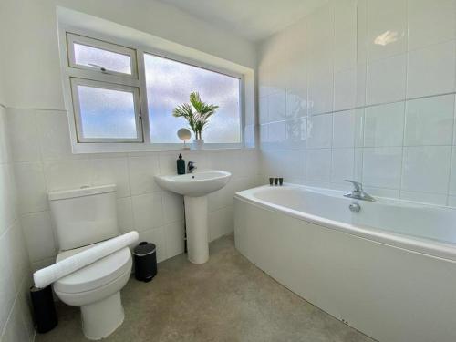 a bathroom with a toilet and a sink and a bath tub at Coventry Huge 4bed 2bath Private Parking NEC by Empower Homes in Coventry
