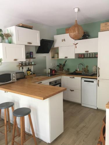 une cuisine avec des armoires blanches et un comptoir en bois dans l'établissement Charmant appartement 42m2 pour location de vacances Seignosse, à Seignosse