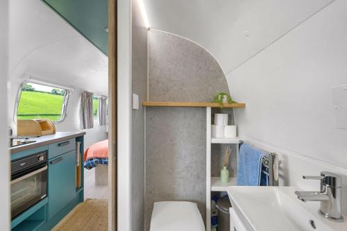 Baño con lavabo y aseo en una caravana en Airstream, Devon Hideaways, en Kenton