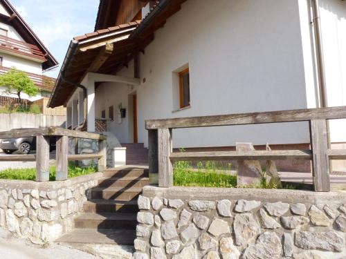 a house with a stone wall and a wooden fence at Apartment Jalps 1 in beautiful Bohinjska Bistrica in Bohinj