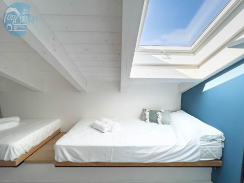 2 Betten in einem weißen Zimmer mit Dachfenster in der Unterkunft San Rocco Sweet Apartments in Muggia
