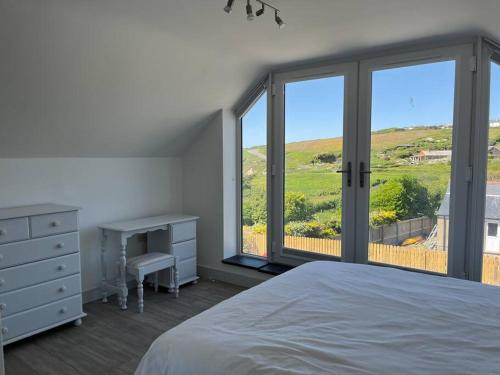 a bedroom with a bed and a desk and windows at Seacliff, Broad Haven. in Broad Haven