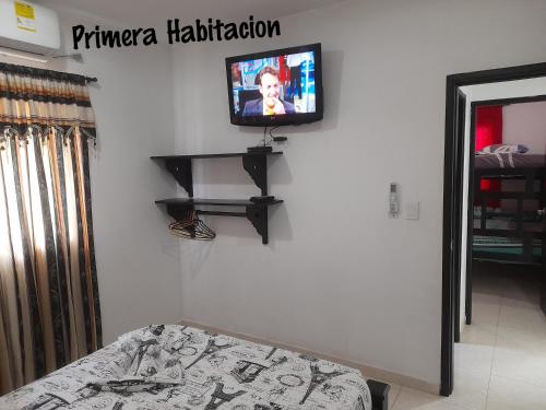 a tv on a wall in a room with a bed at Apartamentos LUISA in Coveñas