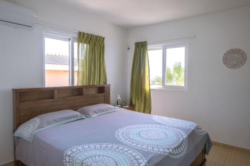 a bedroom with a large bed and two windows at Whitehouse Lagun Apartments in Lagun