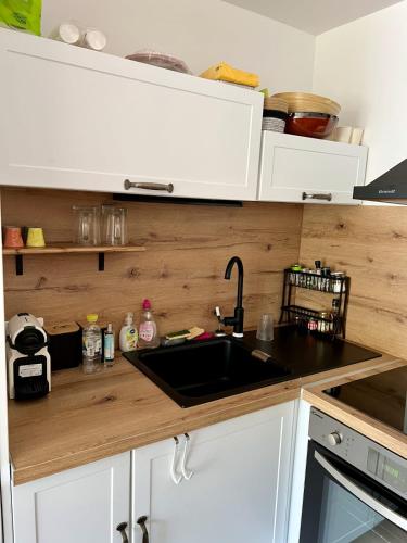 - une cuisine avec un évier et des placards blancs dans l'établissement Les Caravelles - Appartement Une chambre avec parking proche plage, au Grau-du-Roi