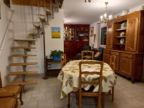 une salle à manger avec une table et un escalier en colimaçon dans l'établissement Nouveau - La grange de Saint-Sulpice, à Bellengreville