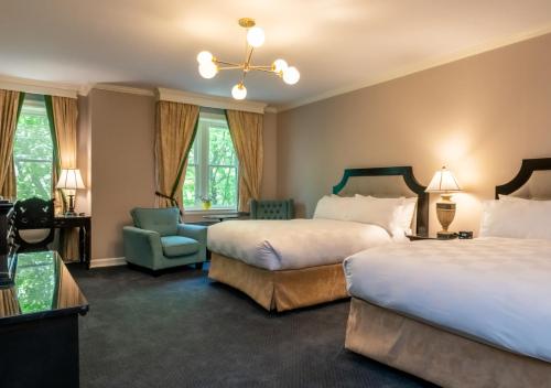 ein Hotelzimmer mit 2 Betten und einem Stuhl in der Unterkunft Castle Hotel & Spa in Tarrytown