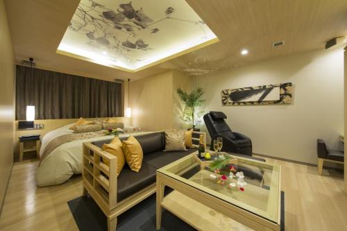 Hotel In The Green (Adult Only) في كيوتو: غرفة نوم بسرير واريكة وطاولة