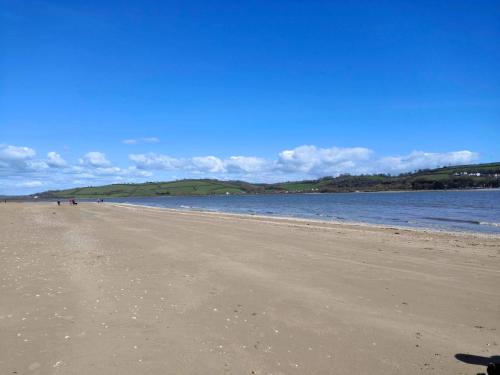 a sandy beach with people walking on it next to the water at Eden Garden in Llangain
