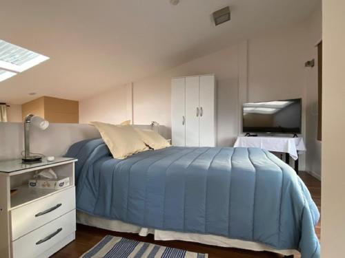 1 dormitorio con 1 cama azul y TV en Estudio en Ushuaia