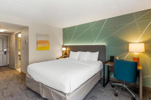 a hotel room with a large bed and a desk and chair at Comfort Inn & Suites Watertown - 1000 Islands in Watertown