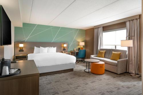 Habitación de hotel con cama y sofá en Comfort Inn & Suites Watertown - 1000 Islands en Watertown