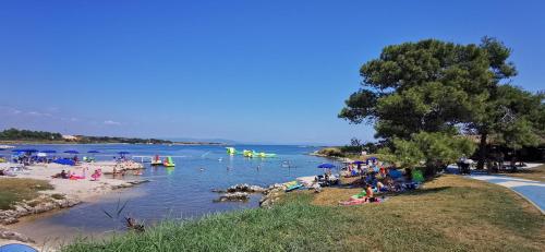 a group of people at a beach with boats in the water at Studio Apartment Lela Ližnjan in Ližnjan