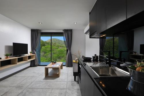 a kitchen with black cabinets and a large window at Utopia Naiharn in Nai Harn Beach