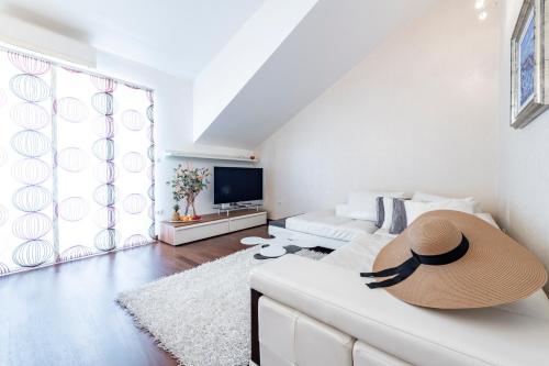 a living room with a white couch with a hat on it at Magic Sunset Suite in Dubrovnik