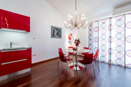 a kitchen with a table with red chairs and a chandelier at Magic Sunset Suite in Dubrovnik
