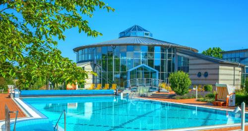 einem Pool vor einem großen Glasgebäude in der Unterkunft Kurhotel Bad Rodach an der ThermeNatur in Bad Rodach