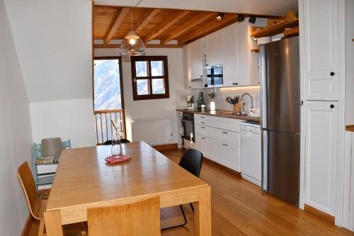 a kitchen with a wooden table and a refrigerator at Appartement moderne vue imprenable in Villard-Reculas
