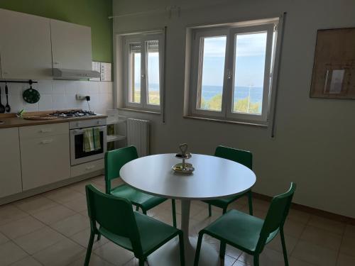 a kitchen with a white table and green chairs at Il Mare di Giò in Monopoli