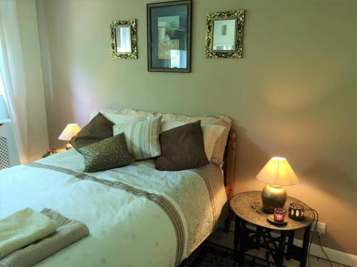 1 dormitorio con 1 cama y 1 mesa con lámpara en 2 Dbl Bed Top Floor Modern Oriental Flat Greenwich Park, en Londres