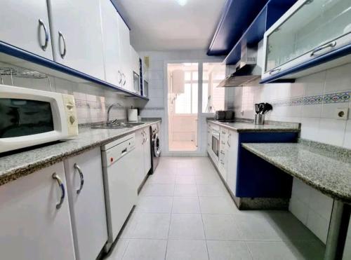 a large kitchen with white appliances and a microwave at Increíble Apartamento Familiar in Mairena del Aljarafe