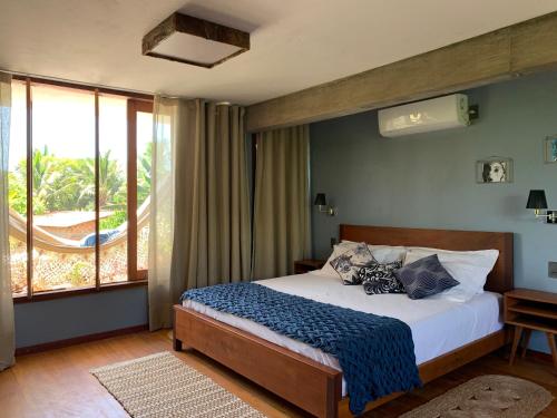 a bedroom with a bed and a large window at Vila das Águas in Atins